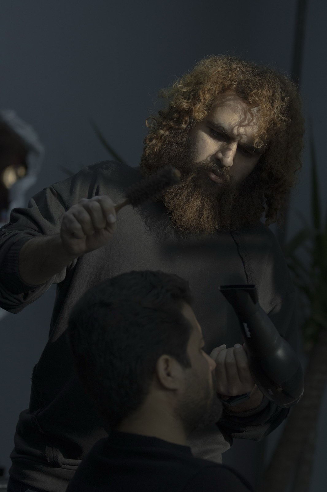 Stylist applying gloss treatment in soft light.